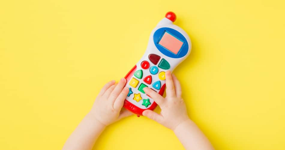 Auf dem Bild sieht man, wie Babyhände mit einem Babytelefon spielen.