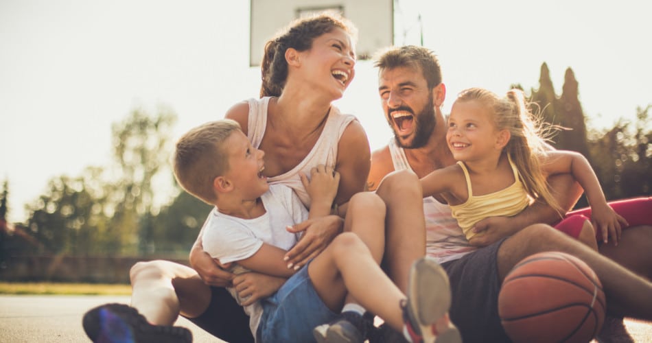 Eine glückliche Familie sitzt auf dem Sportplatz