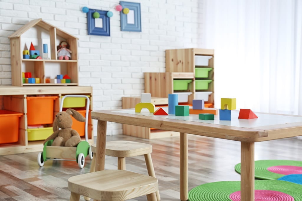 Ein Foto eines aufgeräumten Kinderzimmers. Im Vordergrund steht ein Tisch mit sortiertem Spielzeug.