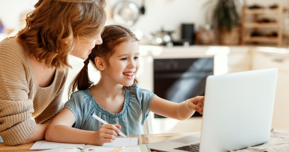Pädagogisch wertvoll oder nicht? Eine Mutter hilft ihrer kleinen Tochter beim Lernen an einem Lerncomputer