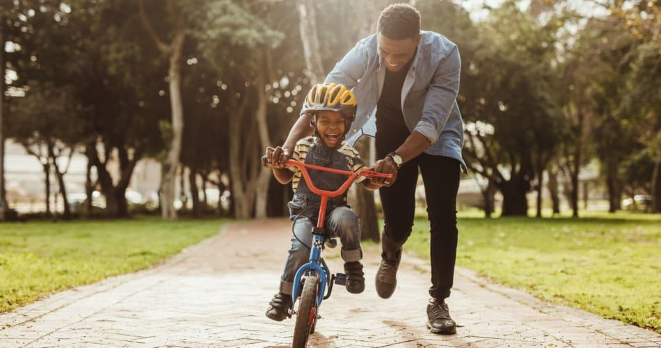 Ein Vater bringt seinem Kind das Fahrradfahren bei.