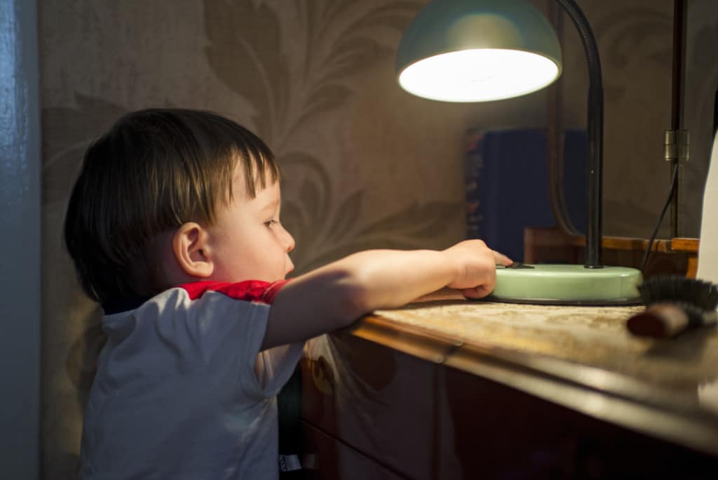 Ein Kind macht eine Tischlampe aus