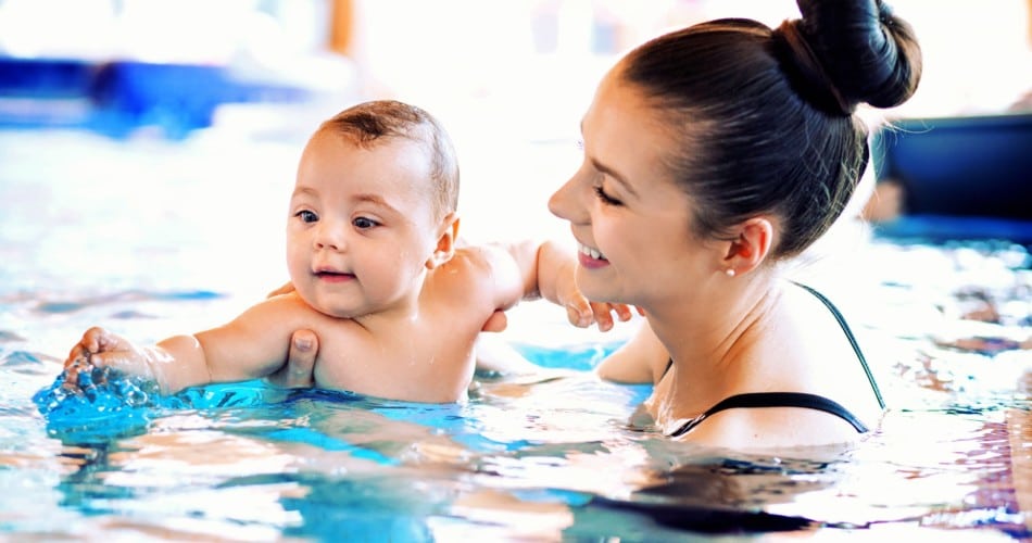 Eine Mutter schwimmt mit ihrem Baby im Schwimmbad.
