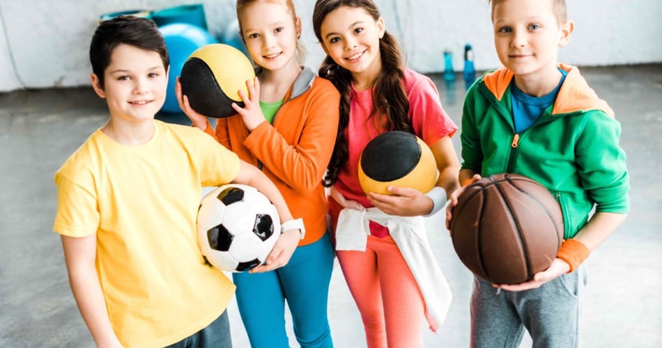 Sport für Kinder nach Alter: Mehrere Kinder haben verschiedene Bälle (Fussball, Basketball etc.) in den Händen.