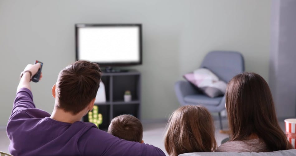 Eltern und der Nachwuchs sitzen vor dem Fernseher und schauen Serien für Kleinkinder an.