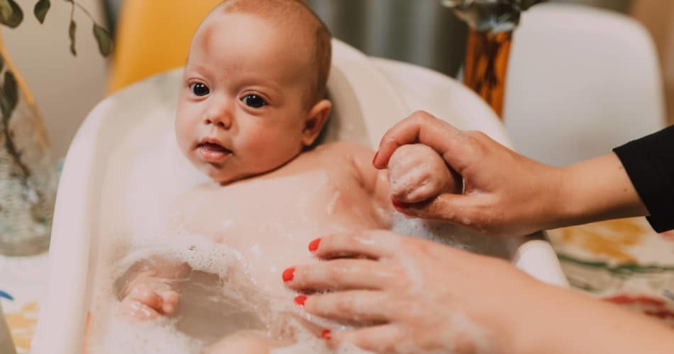 Ein Baby bekommt in einer kleinen Badewanne einen Erkältungsbad.