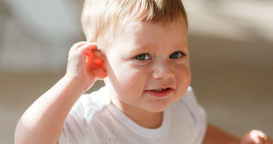 Ein Baby fasst sich ans Ohr.