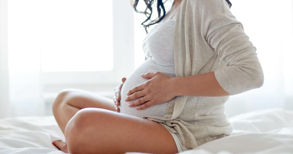 Eine schwangere Frau hält sich den Bauch – Titelbild zu Beitrag, der erklärt, was hilft wirklich, um Wehen zu fördern.