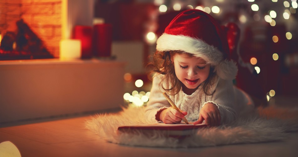 Ein kleines Mädchen schreibt auf eine Wunschzettel-Vorlage zum Ausdrucken ihre Wünsche für Weihnachten an Weihnachtsmann oder Christkind.