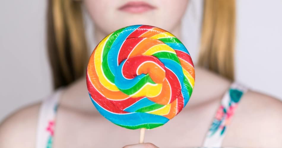 Close-Up eines Lollipops, das ein Mädchen in der Hand hält.