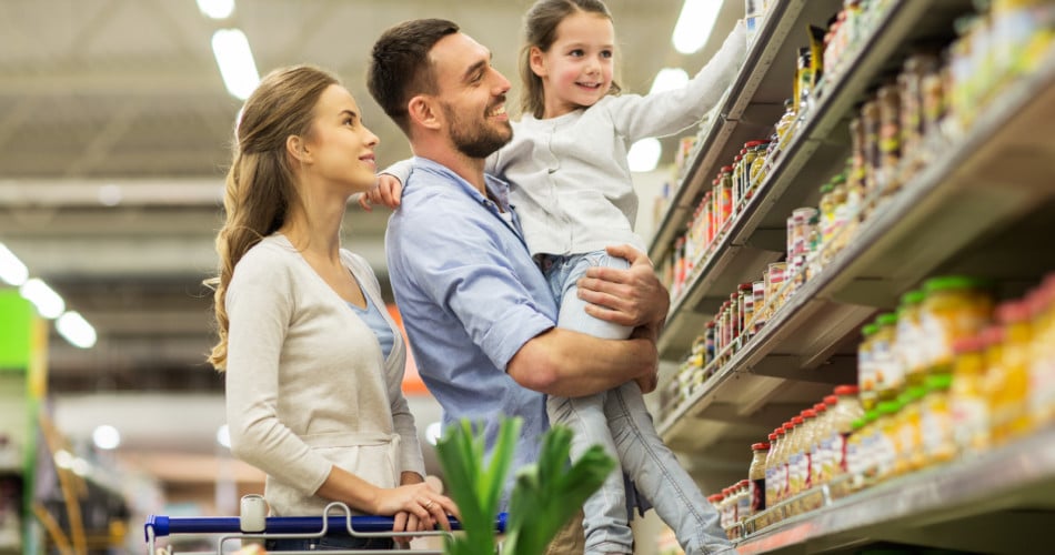 Mutter, Vater und Kind stehen vor einem Supermarktregal