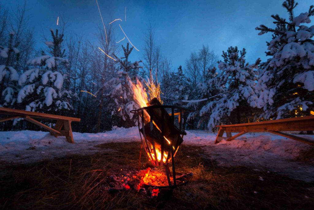 Ein Lagerfeuer vor einer winterlichen Landschaft.
