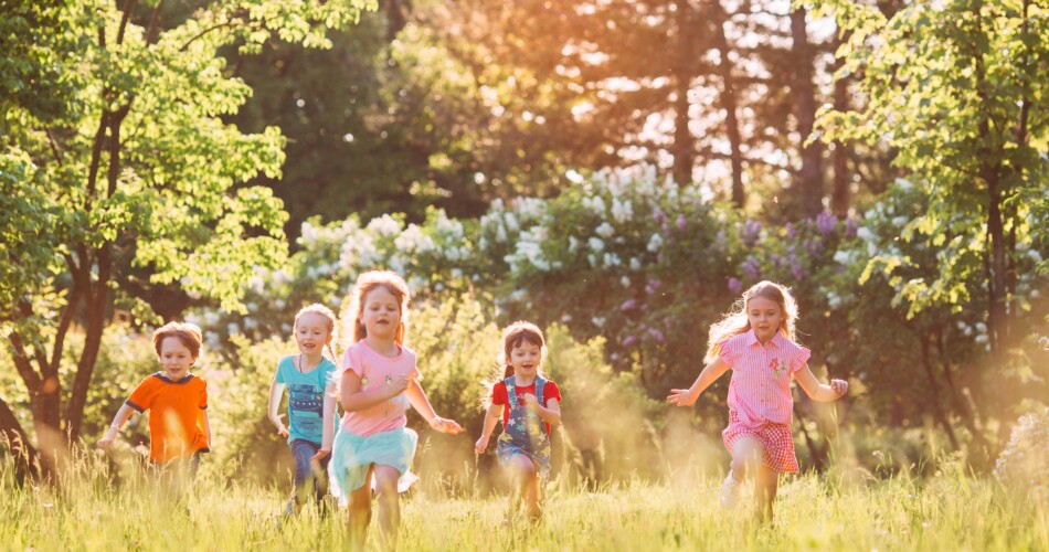 Kinder rennen über eine Blumenwiese.