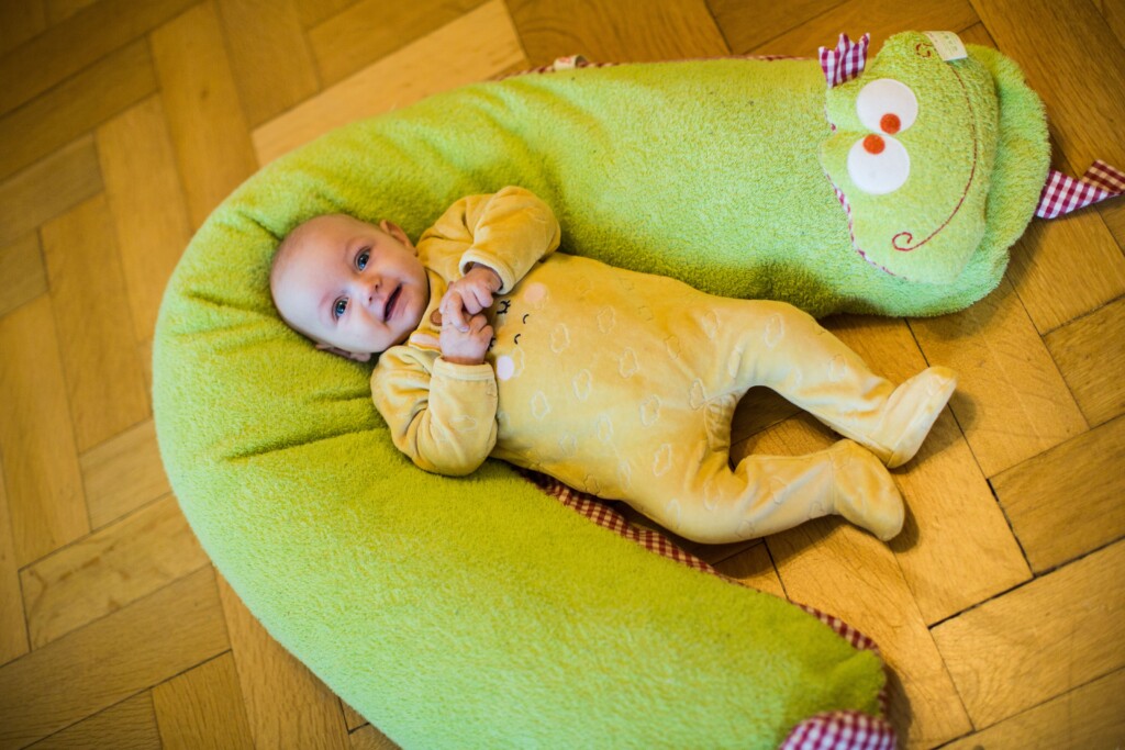 Baby liegt auf einem C-förmigen Stillkissen
