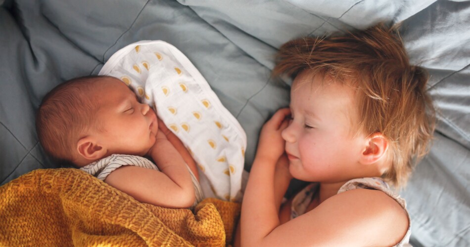 Geschwister, die nebeneinander friedlich Schlafen. Das linke Geschwisterchen ist noch im Babyalter und das rechte ein Kleinkind.