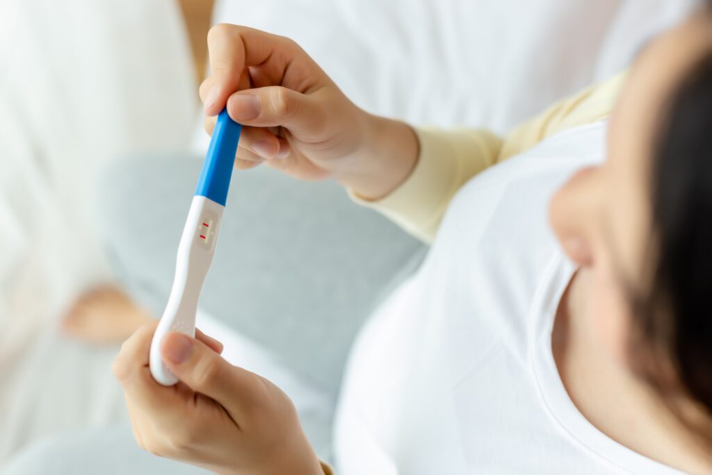 Frau hält einen positiven Schwangerschaftstest in der Hand © Nutlegal - stock.adobe.com