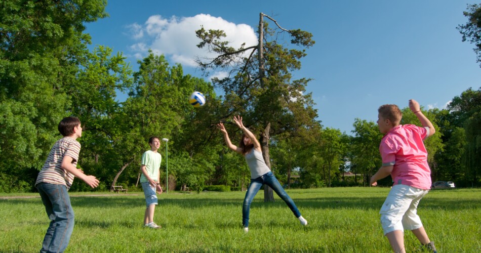 Kinder werfen sich gegenseitig einen Ball zu und fangen ihn.