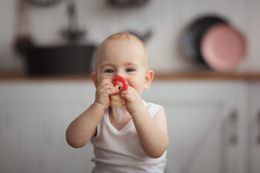 Ein Baby hält sich einen Fruchtsauger mit Netzteil vor den Mund.