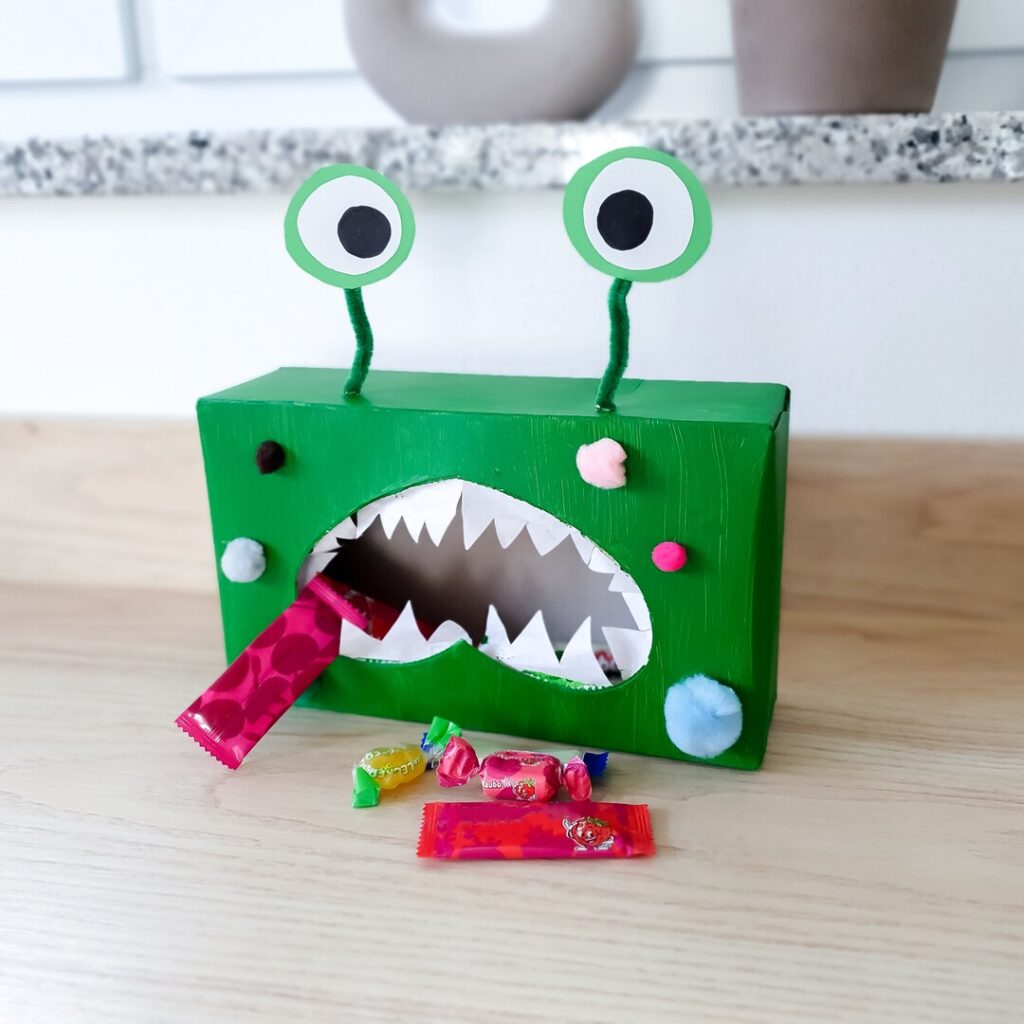 Eine mit Süßigkeiten befüllte Monster-Box mit Kindern für Halloween gebastelt